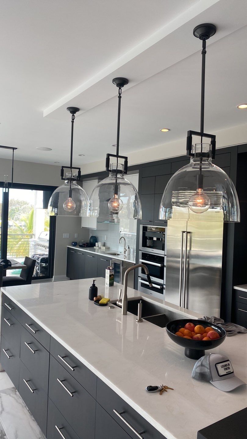 Finished kitchen remodel with dark cabinetry, pendant lighting, and a marble island.